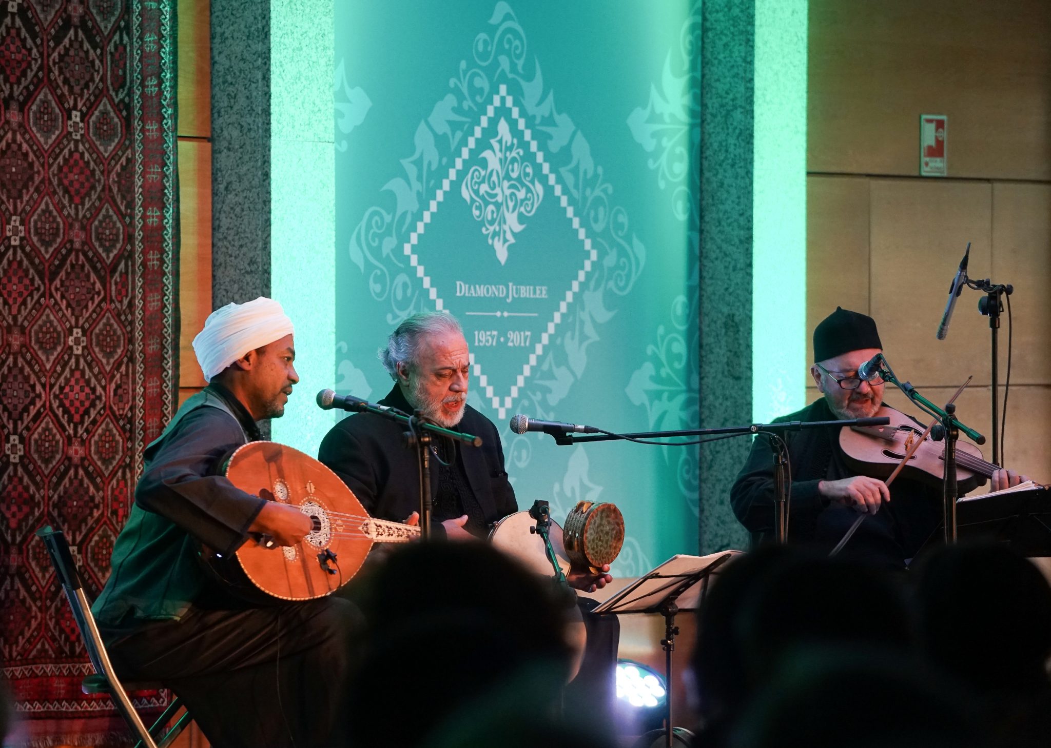 Three men play the lute, darbuka and fidula - respectively from left to right of the observer