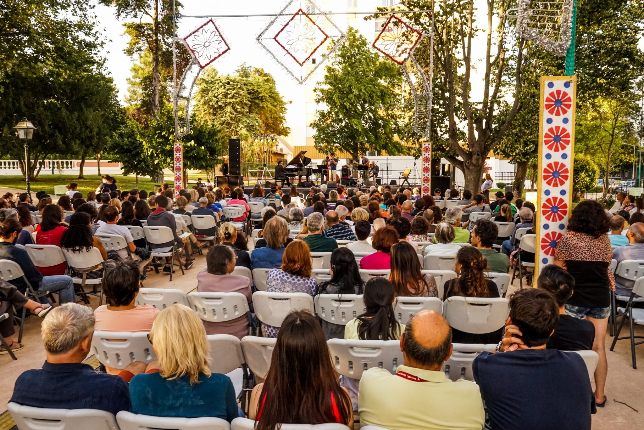 Pessoas sentadas em cadeiras no jardim da Quinta de Santa Clara a assistir a um concerto