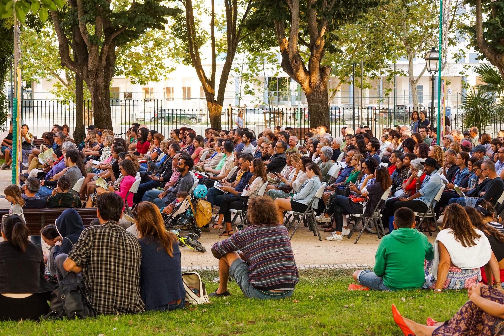 Pessoas sentadas em cadeiras e na relva no jardim da Quinta de Santa Clara a assistir a um concerto